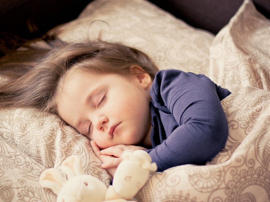 Ein junges Mädchen schläft in eine Bett.